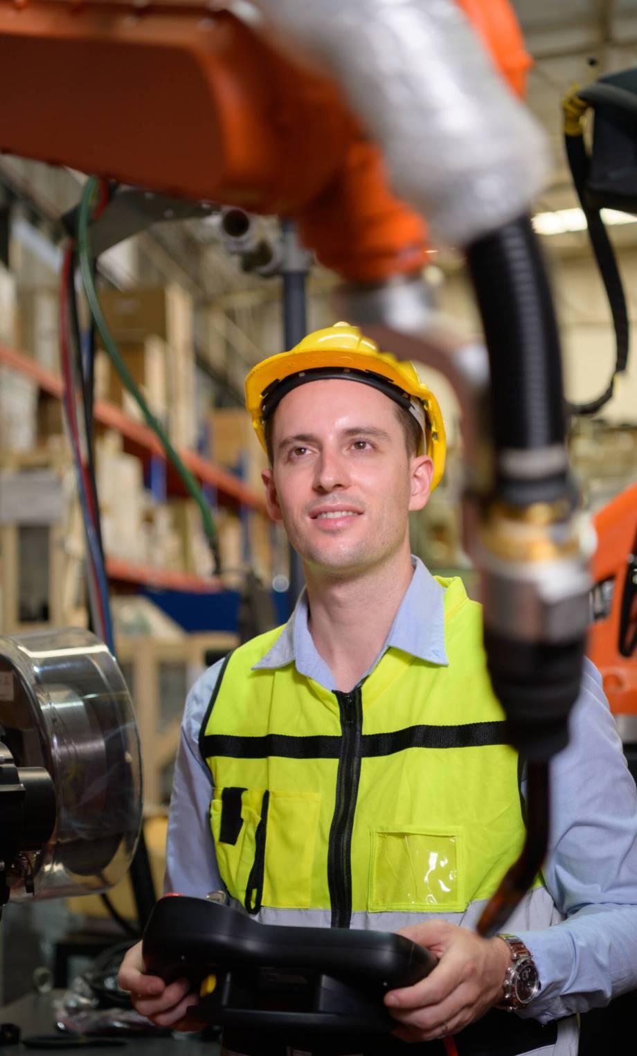 A male worker is controlling a welding robot. by using forcing welding with a control screen which is used for precision welding control. Fast and highly secure